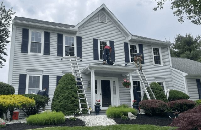 Professional contractors install energy-efficient new construction windows on a two-story suburban home in Pennsylvania to improve curb appeal and insulation.